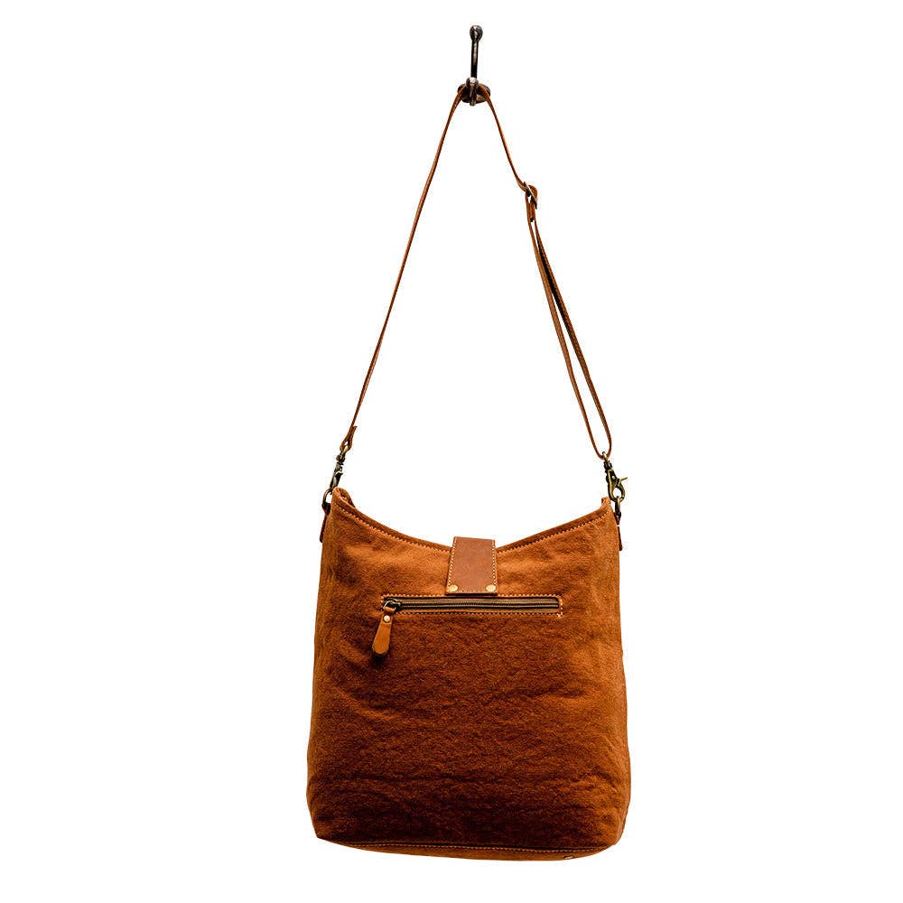 Image of Brown leather handbag with a strap on a white background