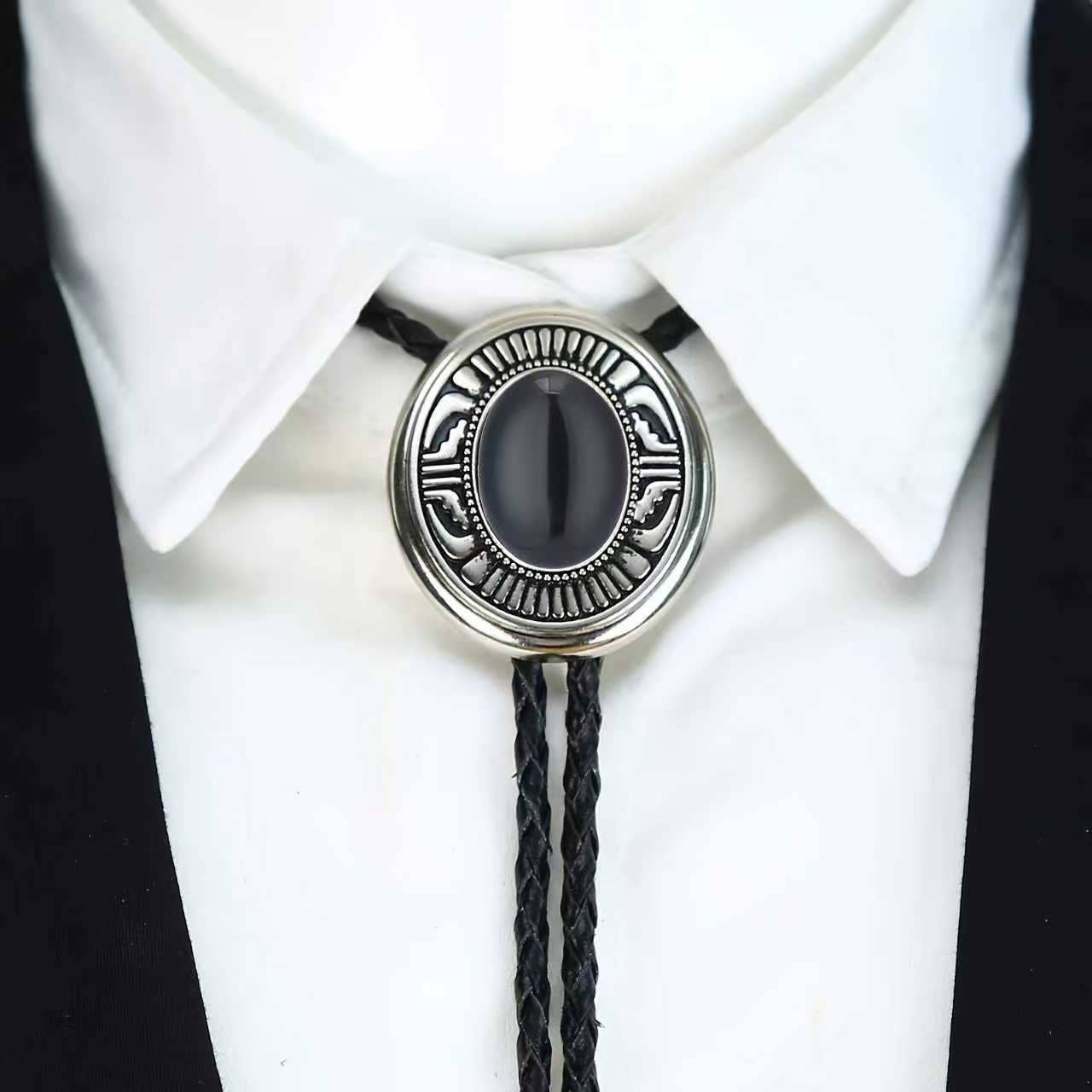 Image of Bolo tie with black stone and silver metal on a white shirt and black tie