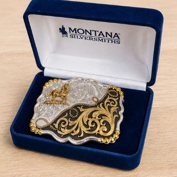 Image of Gold and silver belt buckle in a Montana Silversmiths box on a wooden surface