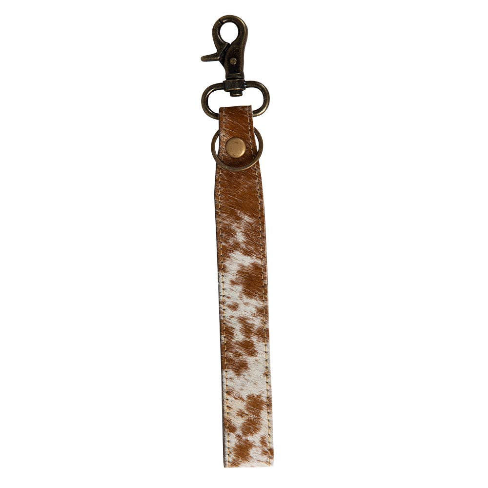 Image of Brown and white cowhide leather key strap with metal clip on a white background