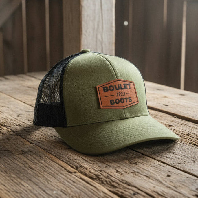 Image of Green and black cap with orange logo on a white background