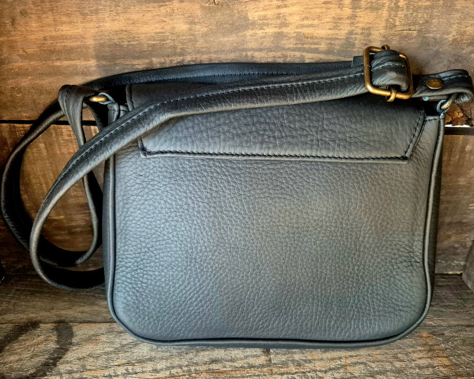Image of Gray leather bag with a gold buckle on a wooden surface