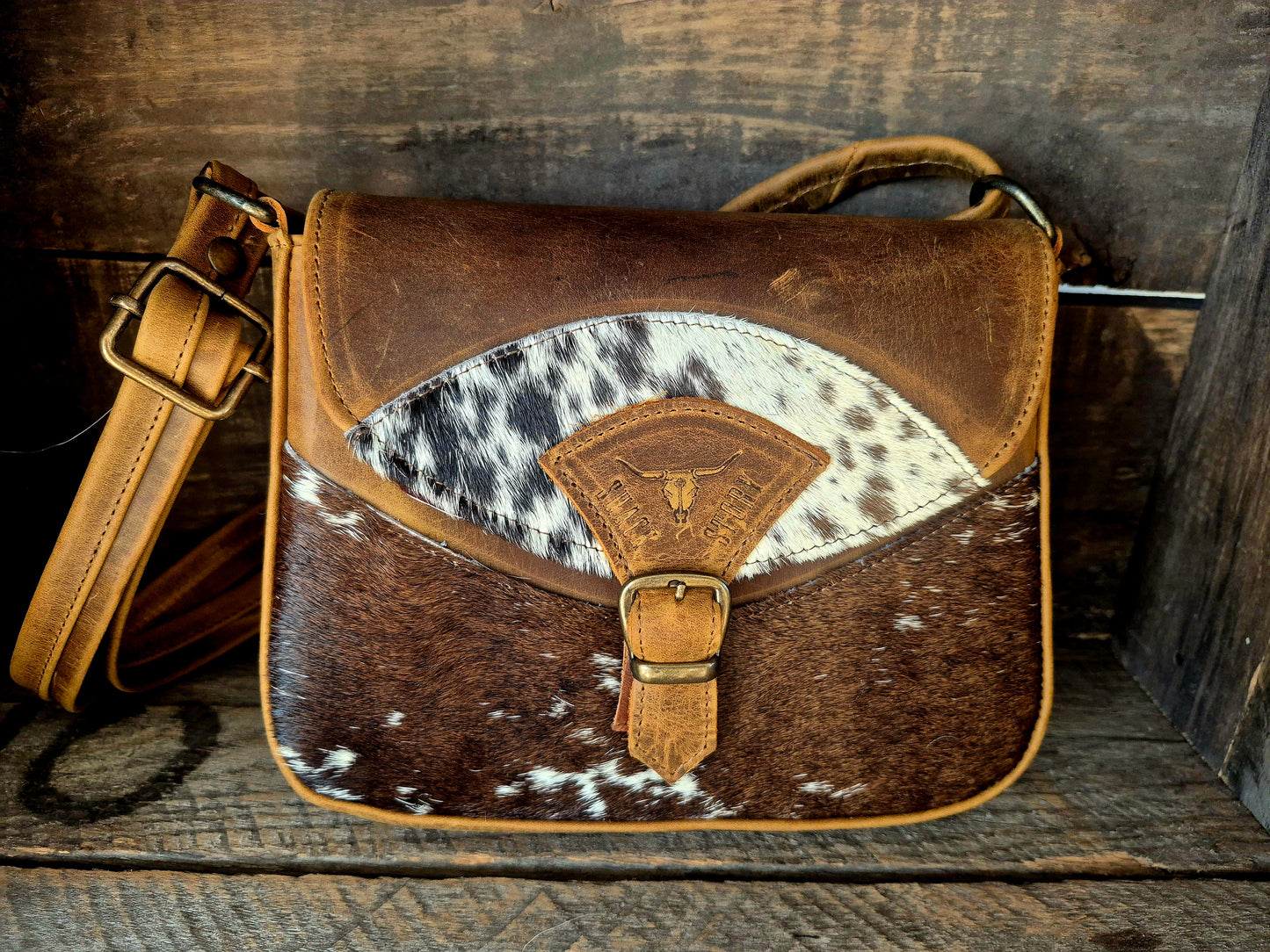 Image of Brown leather bag with cowhide pattern on a wooden surface